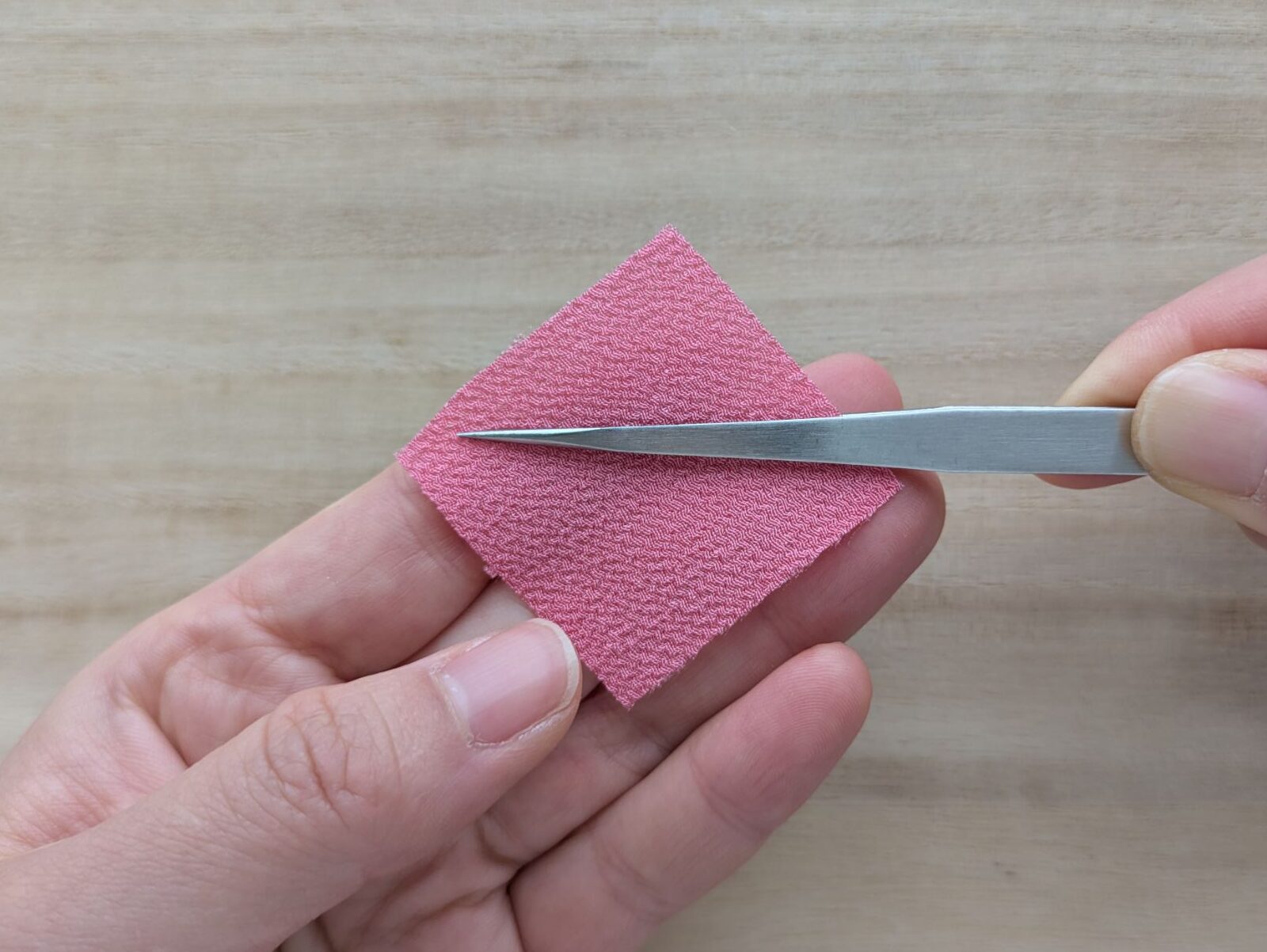 ピンクの四角形の布をピンセットではさむ