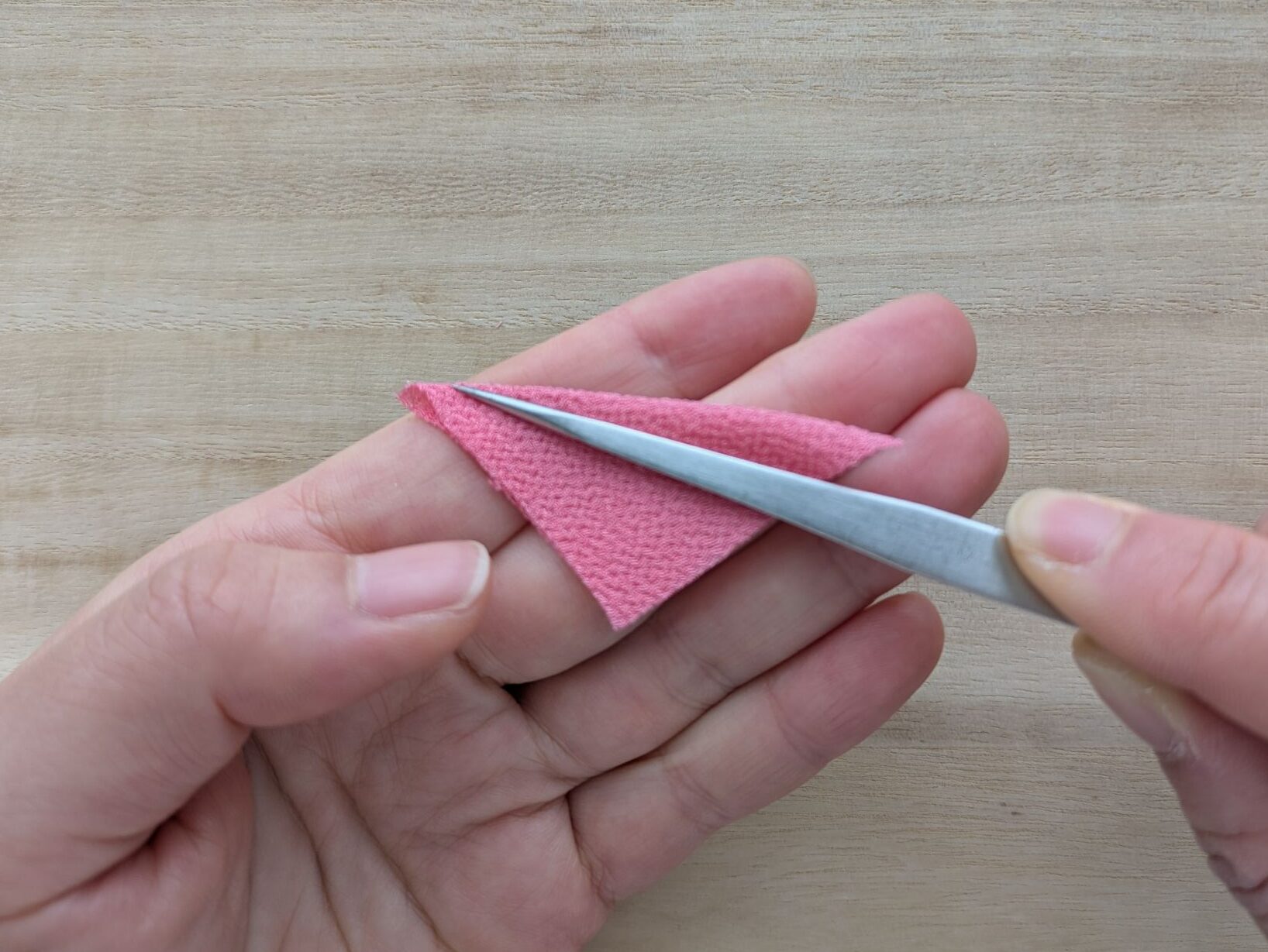 ピンクの四角い布を三角形に折ったところ
