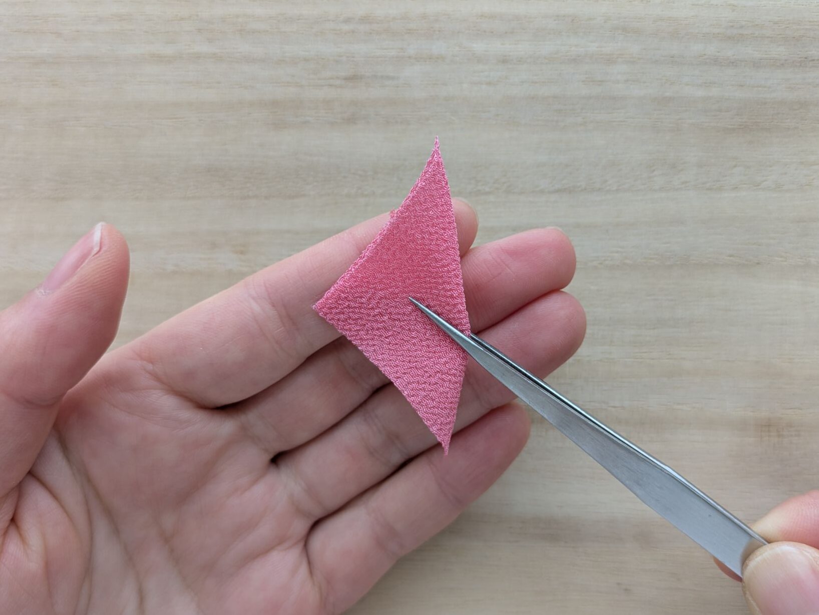 ピンクの三角形の布の向きを変える