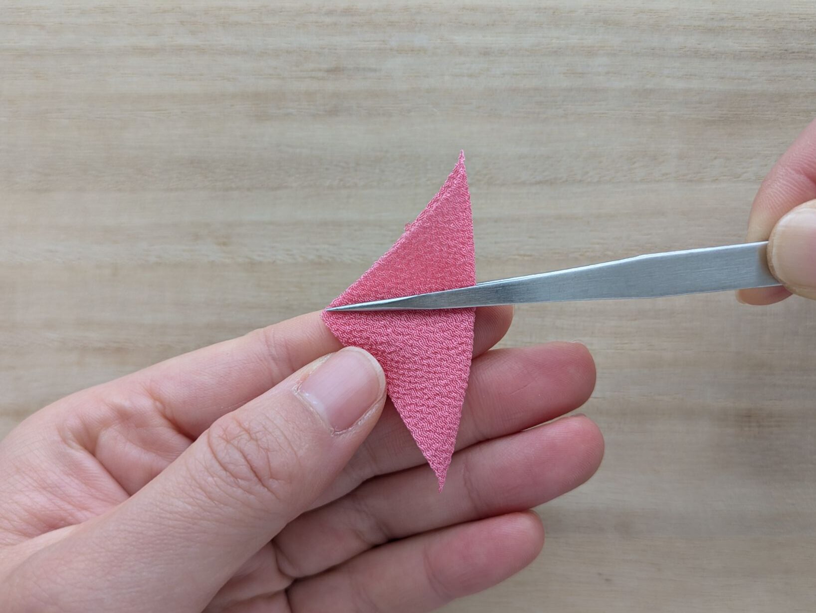 ピンクの三角形の布の真ん中よりやや上を持つ