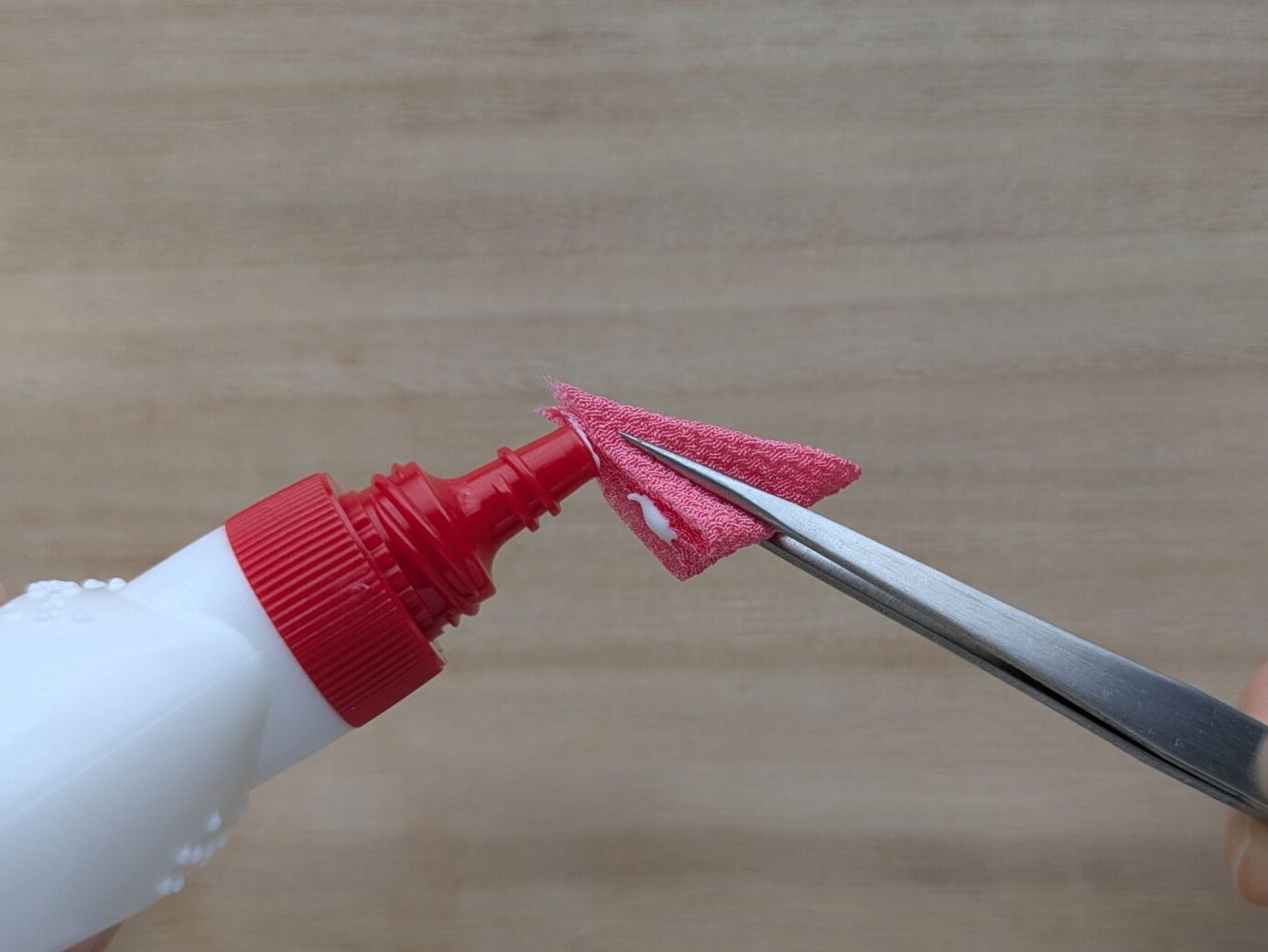 ピンクの布の切り口にボンドをつける