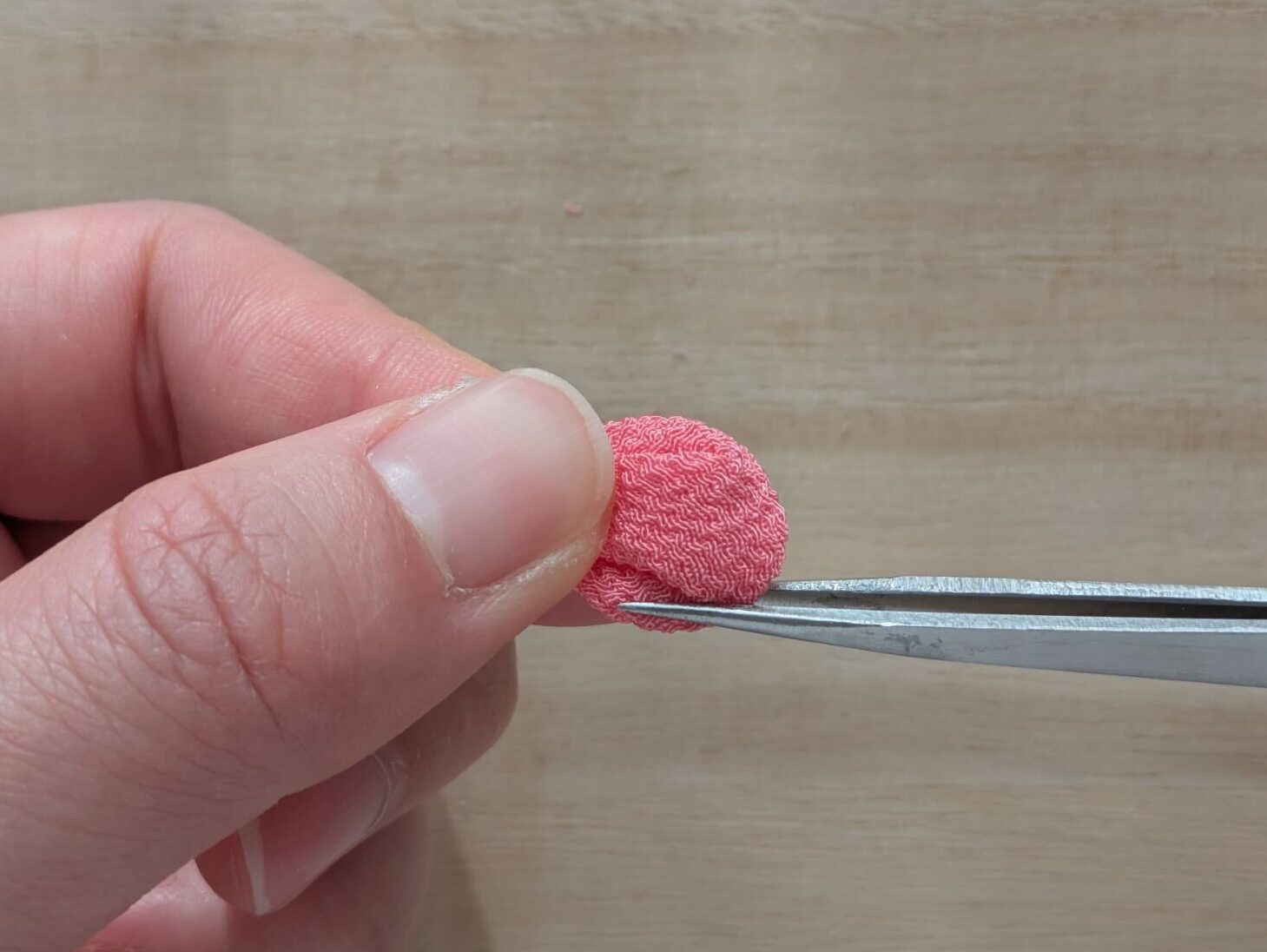 ピンクの丸つまみの丸みのある右端を裏返しているところ