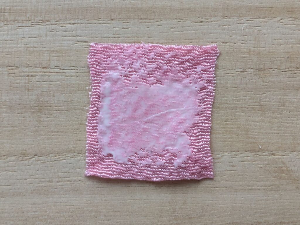 ピンクの布の一面にボンドを塗ったところ