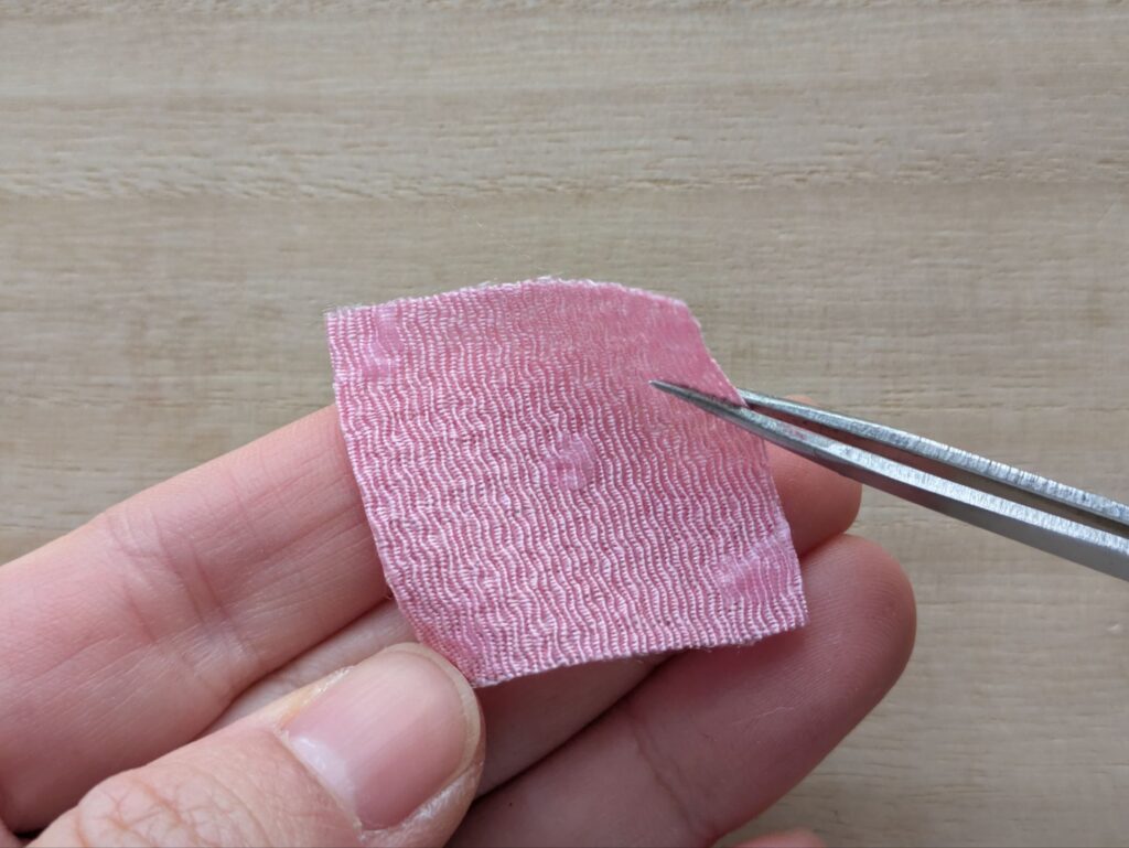 ピンクの布を手に持っている