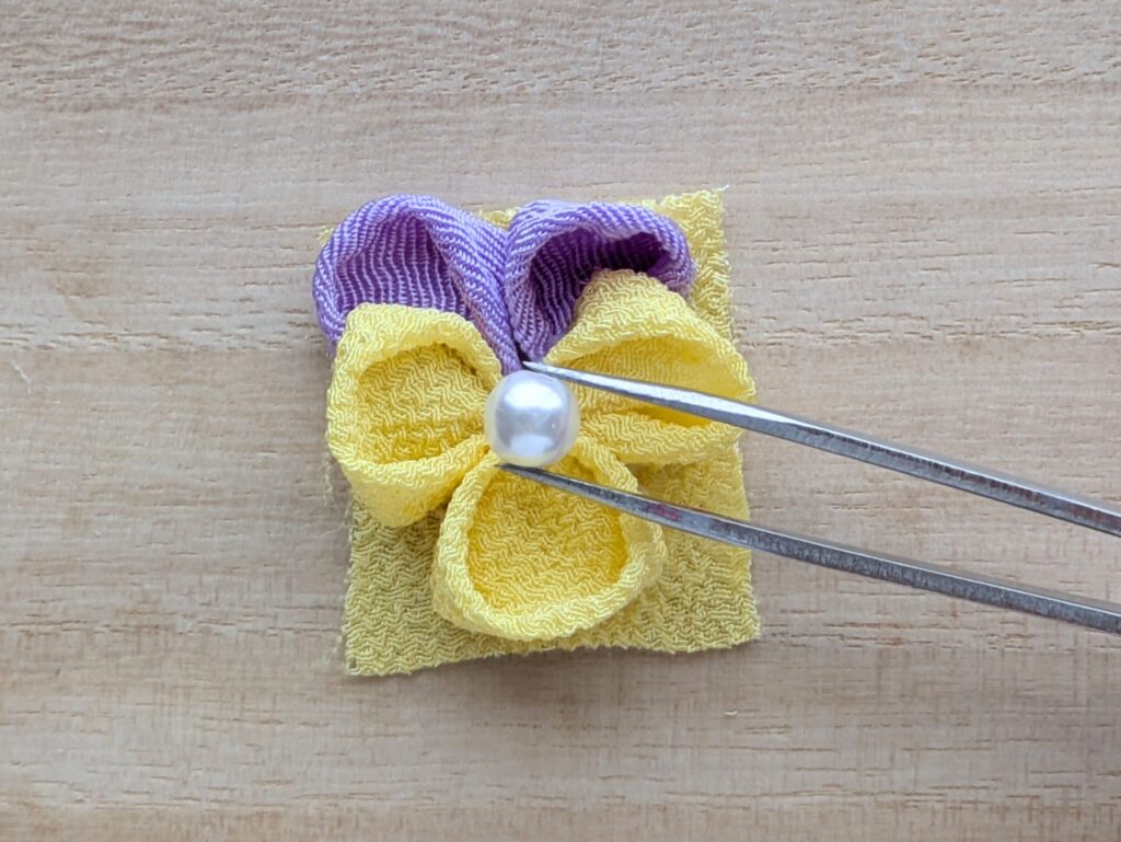 つまみ細工で作ったパンジーの花の中心にパールを置く工程
